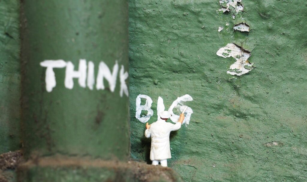 Person writing "THINK BIG" on a wall