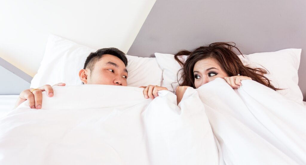 Couple laying in bed looking at each other